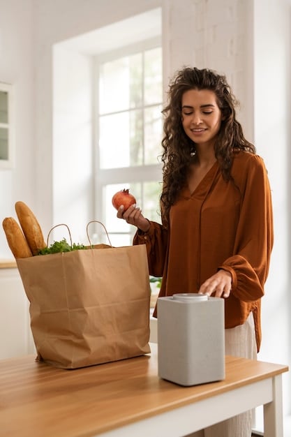A person using a smart speaker to order groceries. The speaker is placed on a kitchen counter, and the person is interacting with it while preparing a meal. The scene depicts the convenience and ease of use of voice commerce in everyday life.